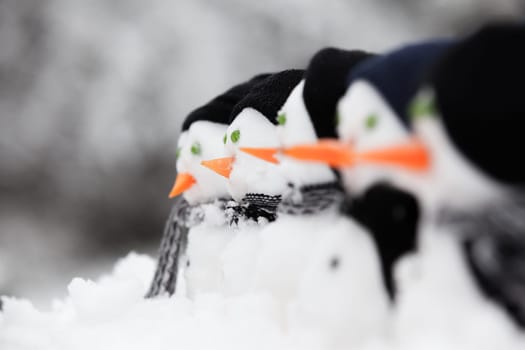 Row of snowmen looking to the left in the snow in winter