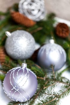 Silver Christmas tree balls in green fir branches with white shiny snow as macro detail