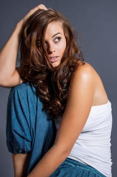 Young attractive brunette woman with curls and white top as portrait