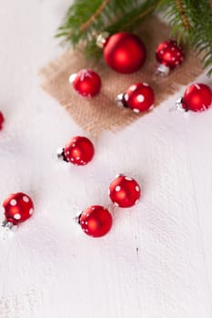 Beautiful red Christmas balls with small white dots with green fir branches on a jute sack