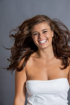 Young attractive brunette woman with curls and white top as portrait