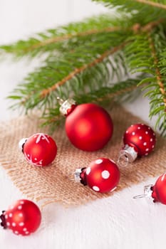 Beautiful red Christmas balls with small white dots with green fir branches on a jute sack