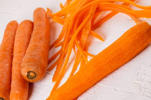 Fresh orange carrots beet turn beets peeled with peelers and bowls on a white wooden board