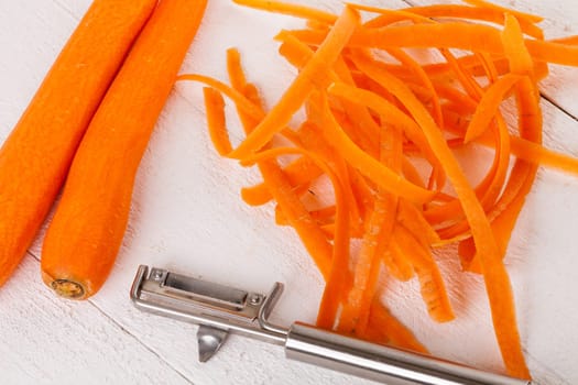 Fresh orange carrots beet turn beets peeled with peelers and bowls on a white wooden board