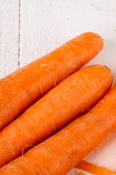Fresh orange carrots beet turn beets peeled with peelers and bowls on a white wooden board