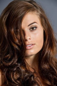 Young attractive brunette woman with curls and white top as portrait