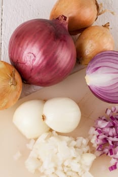 White and red onions peeled and with slurs as a whole and in cubebrunoise as a close-up on cutting board