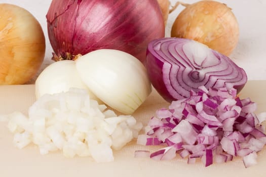 White and red onions peeled and with slurs as a whole and in cubebrunoise as a close-up on cutting board