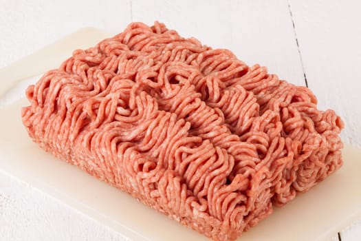 Minced meat raw beef and pork mixed as a block of protective atmosphere as a close-up on a white plate