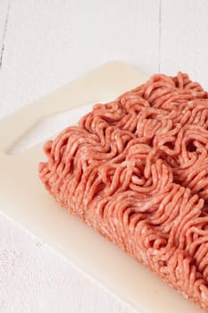 Minced meat raw beef and pork mixed as a block of protective atmosphere as a close-up on a white plate