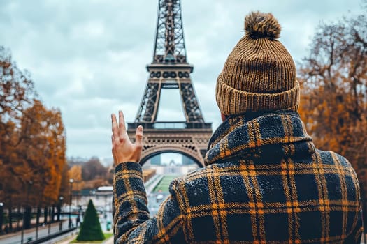On a cloudy day in Paris, a person in a stylish coat waves goodbye to the Eiffel Tower, framed by golden autumn foliage and cityscape.