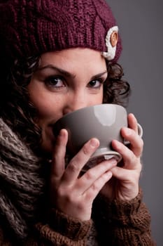 it's winter and this girl with wool hat and scarf drinks a hot chocolate or hot tea or milk from a big mug and she's happy