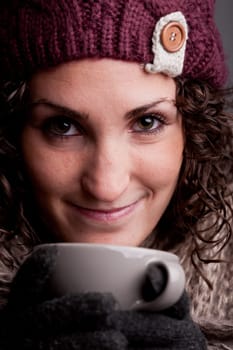 it's winter and this girl with wool hat and scarf drinks a hot chocolate or hot tea or milk from a big mug and she's happy