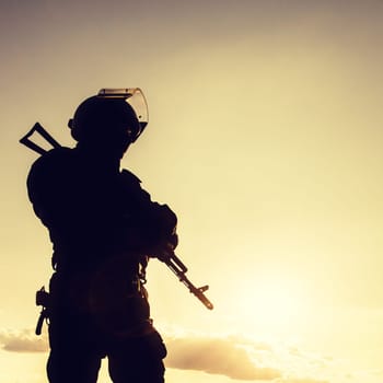 Silhouette of police officer with weapons at sunset