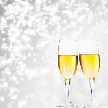 Glasses with champagne against holiday lights and clock close to midnight