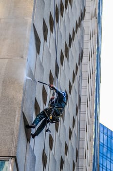 Washer wash the windows of modern skyscraper, high risk work