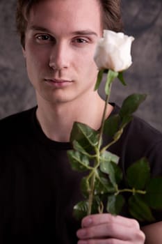 young fascinating man with a white rose looking good