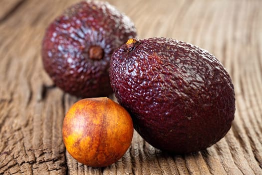 Close up view of two ripe avocados and avocado stone on an old rustic wooden plank