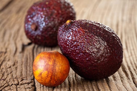 Two ripe avocados and avocado stone on an old rustic wooden plank