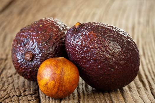 Close up view of two ripe avocados and avocado stone on an old rustic wooden plank
