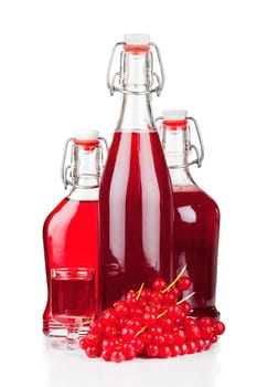 Ripe red currants and syrup or liqueur in a glass and swing top bottles isolated on white background