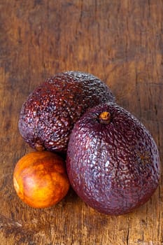 Close up view of two ripe avocados and avocado stone on an old rustic wooden plank