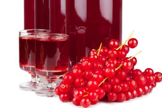 Close-up view of ripe red currants and syrup in a glass and bottles isolated on white background