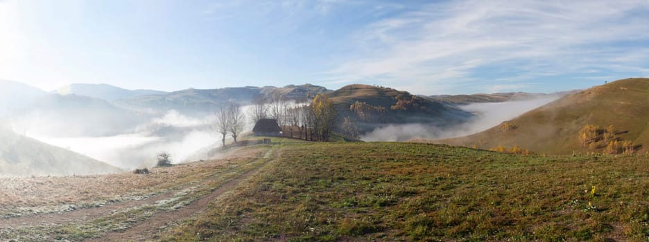 Panoramic view of  Small cottage in the mountains in a foggy autumn morning