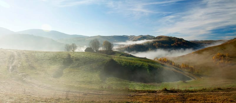 Panoramic view of  Small cottage in the mountains in a foggy autumn morning