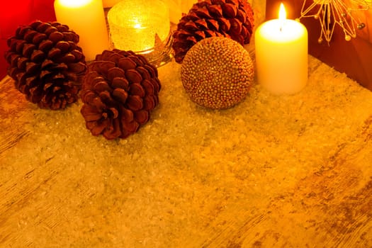 Wooden Christmas background with candles, pine cones, shopping bags and baubles..