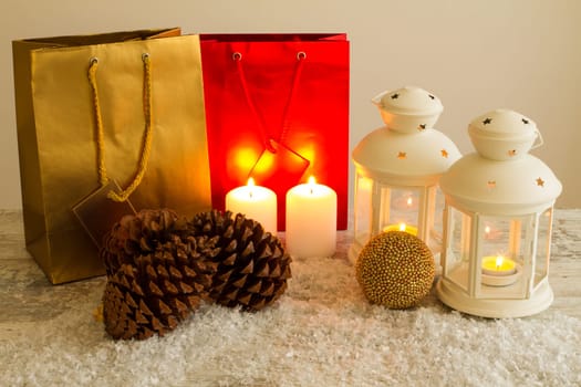 Christmas setting with candles, pine cones, shopping bags and baubles..