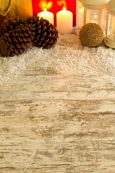 Wooden Christmas background with candles, pine cones, shopping bags and baubles..
