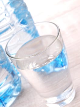 Fresh water in a glass with bottles in background