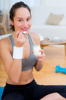 View of a Attractive sportive woman eating yoghurt after sport