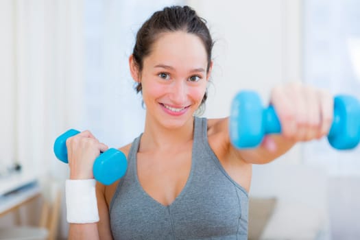 View of a Young attractive girl doing exercise at home with dumbell