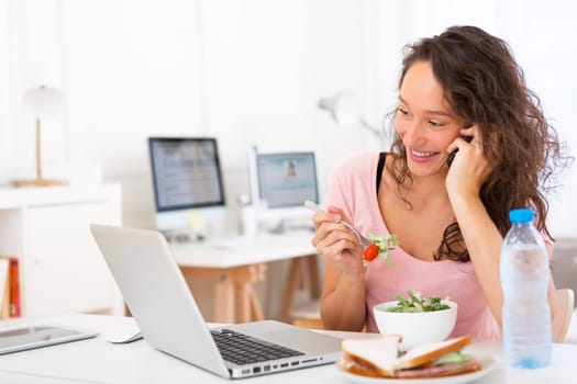View of a Young attractive student eating salad while phoning