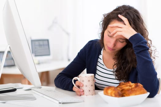 View of a Young tired student taking breakfast while working