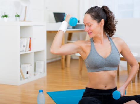 View of a Young attractive girl doing exercise at home with dumbell