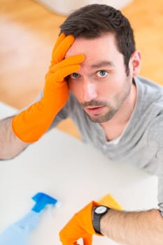 View of a Young attractive man cleaning his flat
