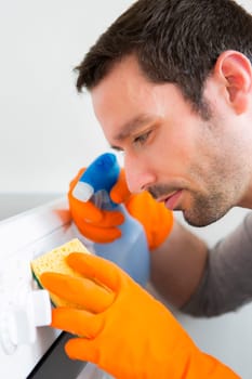 View of a Young attractive man cleaning his flat