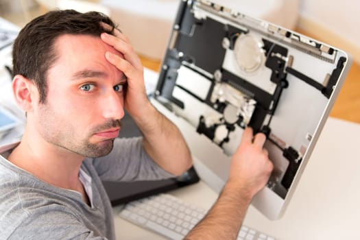 View of a Young attractive man trying to repair computer