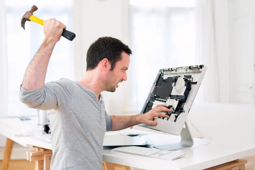 View of a Young attractive man angry against computer