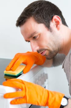 View of a Young attractive man cleaning his flat