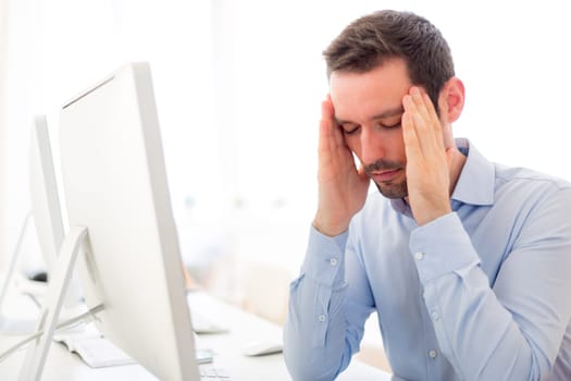 View of a Young attractive man got a headache at the office
