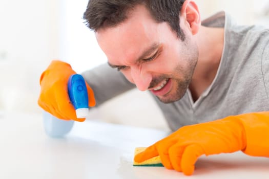 View of a Young attractive man cleaning his flat