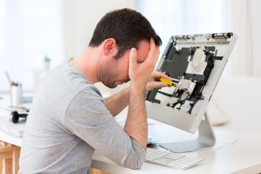 View of a Young attractive man trying to repair computer