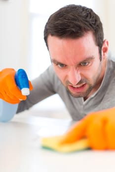 View of a Young attractive man cleaning his flat