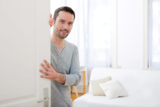 View of a Young attractive man welcoming you in his house