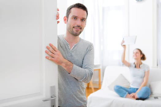 View of a Young attractive man welcoming you in his house