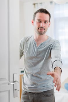 View of a Young attractive man welcoming you in his house